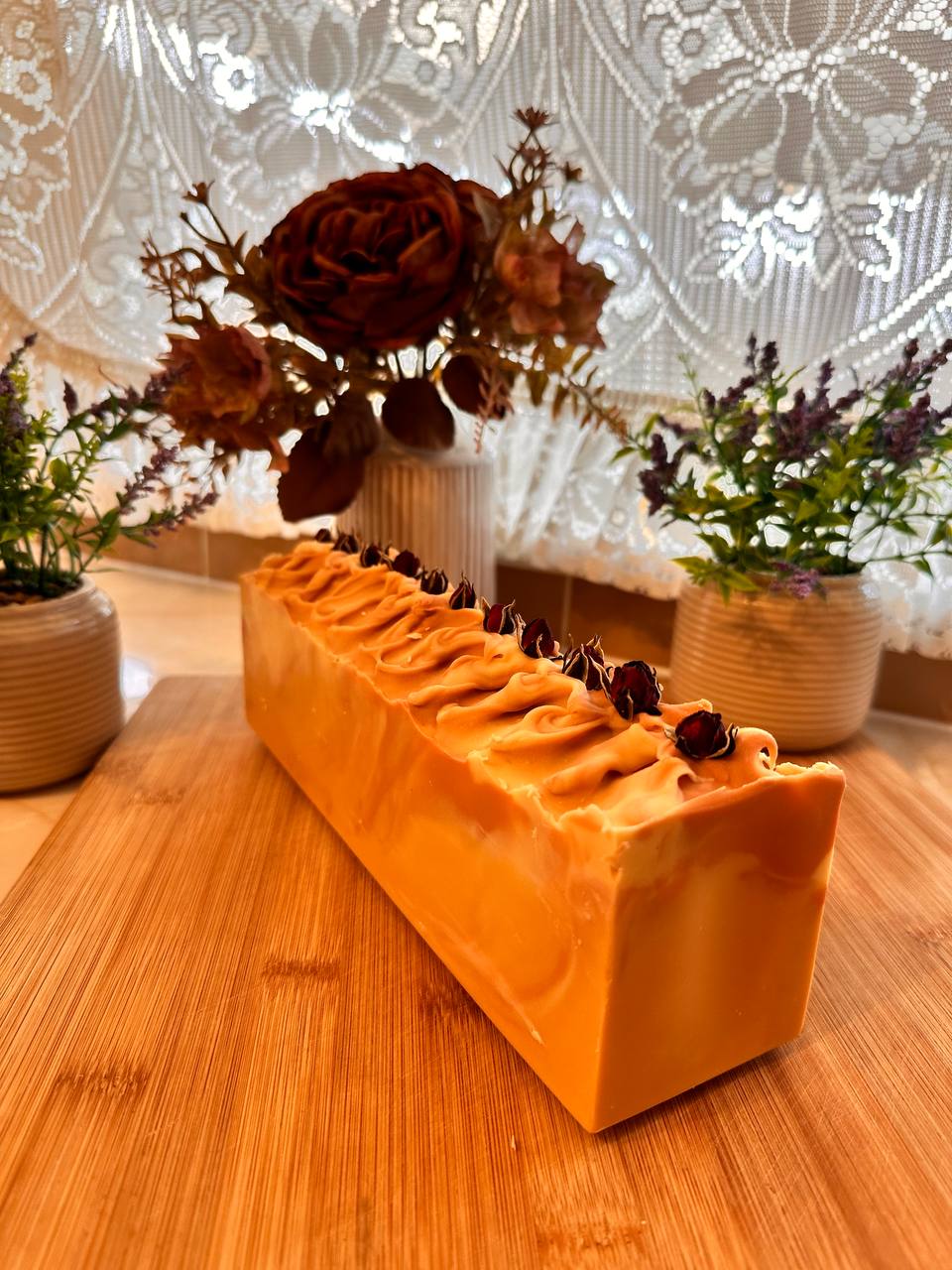 LUMÉA Sandalwood luxury handmade soap UK loaf styled on a rustic wooden board with dried roses, soft linen and warm candlelight.