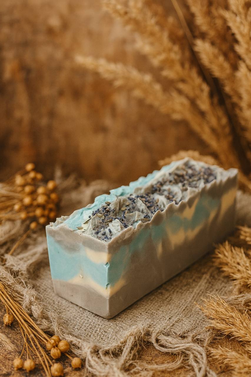 Handcrafted LUMÉA Fresh Linen Breeze artisan soap with marbled blue and cream design, styled on linen with dried flowers — boho luxury aesthetic.