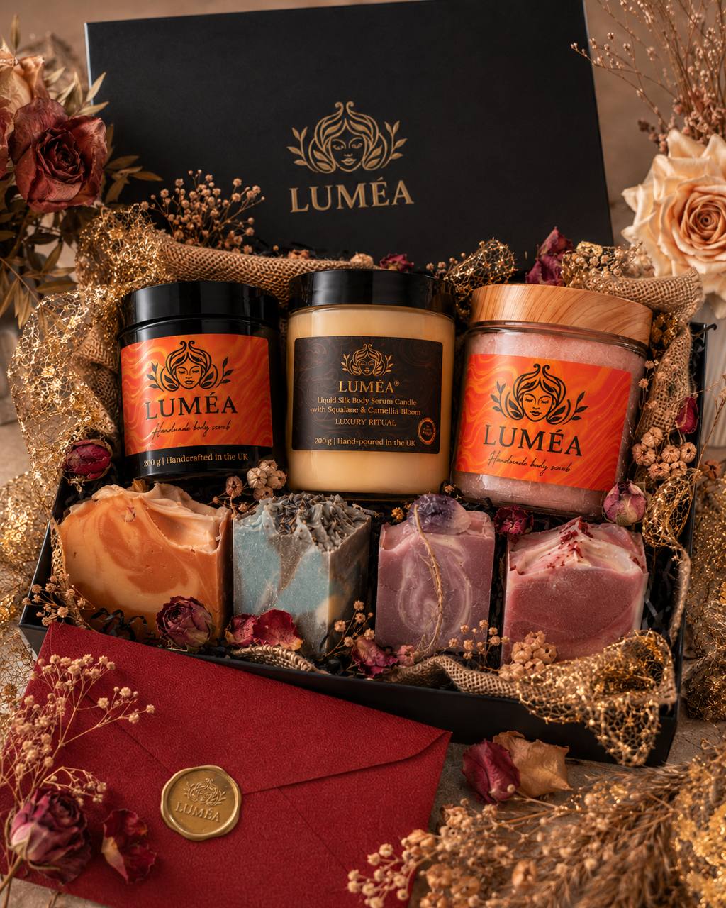Luxury LUMÉA London skincare gift set with handmade body scrubs, body serum candle, artisan soap bars, black gift box, gold detailing and dried flowers