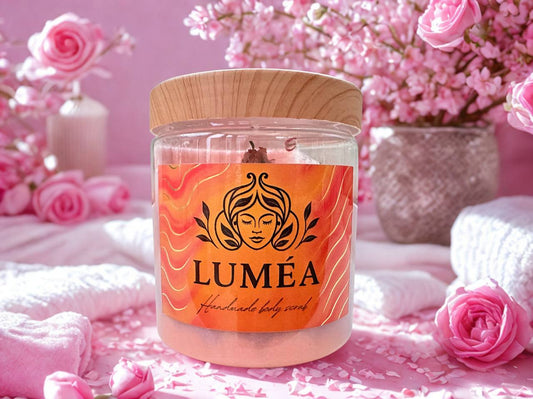 LUMÉA  Peony Kiss Dead Sea salt body scrub with romantic floral scent.LUMÉA natural scrub jar with Dead Sea salts, surrounded by candles and spa decor, promoting organic skincare and relaxation.