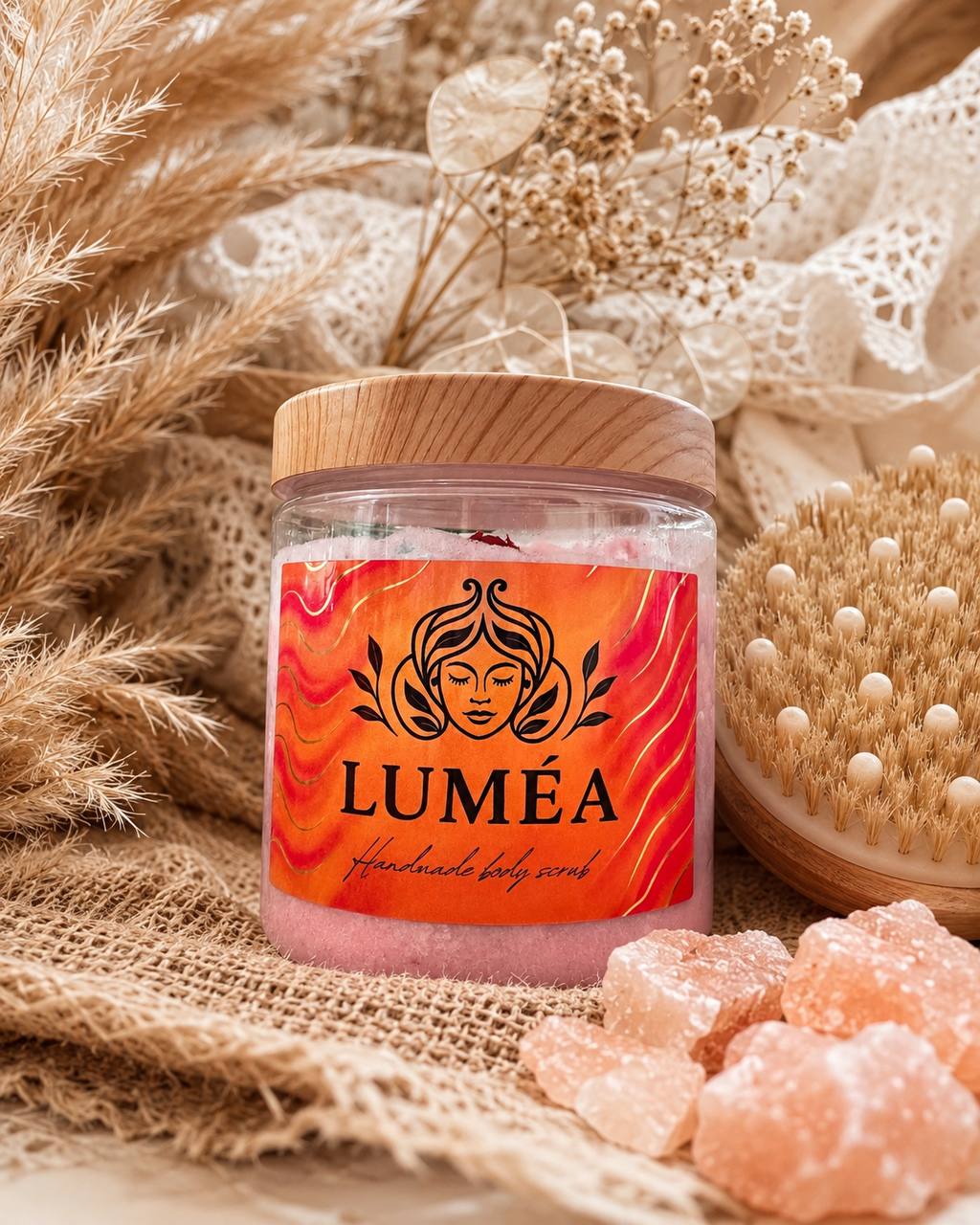 LUMÉA handmade body scrub in a clear jar with wooden lid, beautifully styled in a luxury boho spa setting with dried flowers, pampas grass and a natural body brush, showcasing premium handmade skincare.